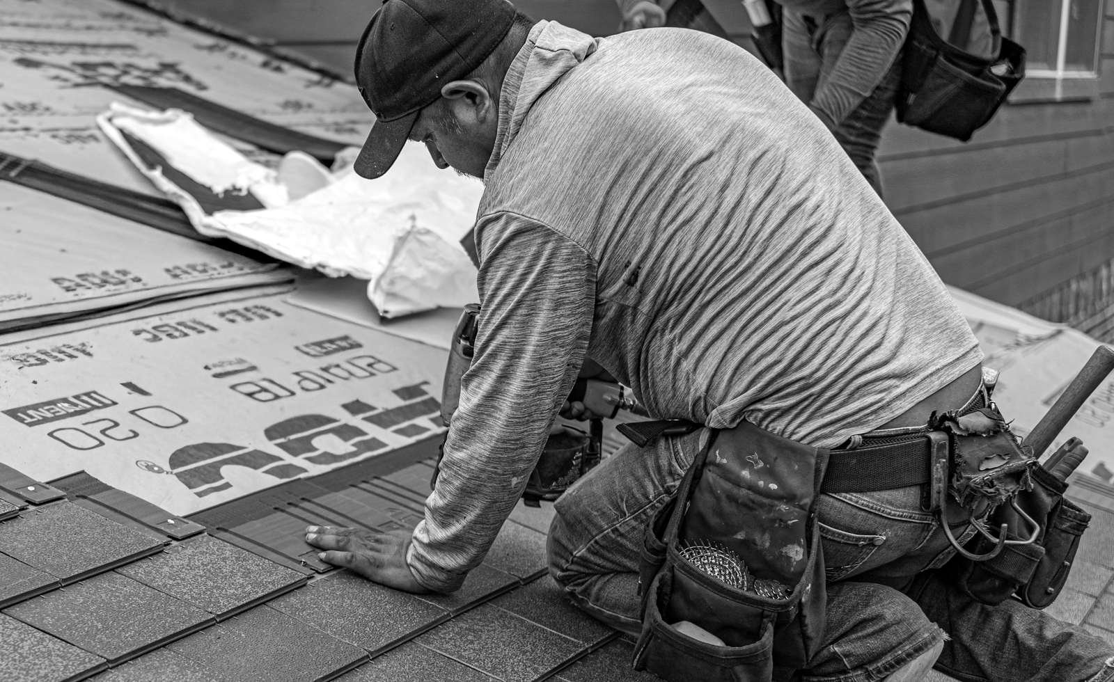 A roofer installing shingles on a house roof